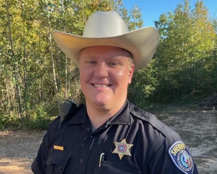 Austin Kahil ('19) A man smiling at the camera in sheriff clothes and a cowboy hat on with nature in the background