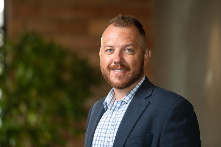 Chris Davis ('07) Alumni Spotlight A man smiling at the camera outside.