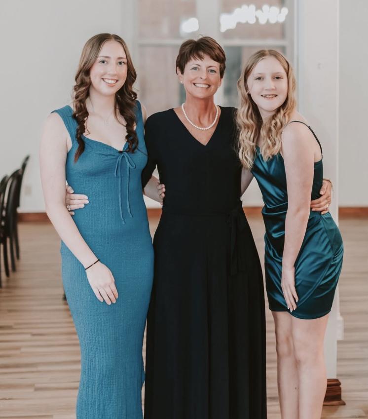 Woman standing hugging her two daughters