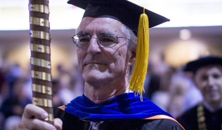 Professor dressed in academic regalia holding a mace. Darville2