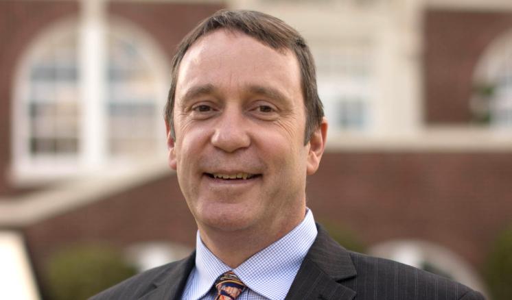 Man smiling at the camera with a building in the background
