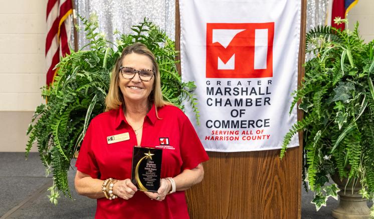 Woman posing with employee of the year award smiling at the camera