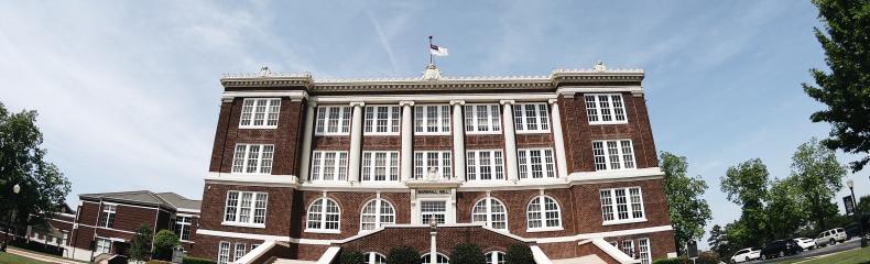 Red brick building with blue sky and green grass from below.
